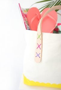 Transform a regular canvas tote bag into a DIY Leather Strap Tote Bag with the addition of leather and a few basic crafting supplies.